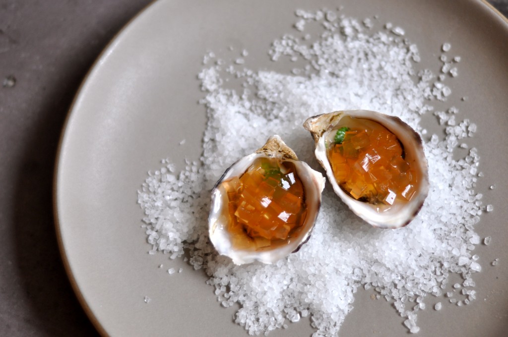 Oysters on the half shell with a tiny leaf of cilantro covered in rasam gelee